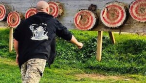 Lanceur de haches en action face à une rangée de cibles en extérieur